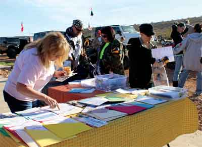 Volunteers sign up and get trail maps during a clean up event at Logandale Trails area on Saturday. PHOTO BY MAGGIE MCMURRAY/Moapa Valley Progress.