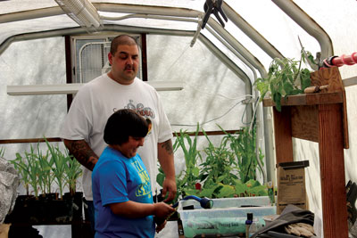 Kaluna Aki carefully helps his son Jacob water the starts for the ag barn gardening exhibit for the fair. PHOTO BY MAGGIE MCMURRAY/Moapa Valley Progress.