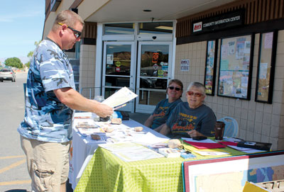 Local resident Jon Zerkle picks up maps and information at a booth outside of Lin’s Marketplace manned by MVRP member Marjorie Holland and PIC Administrator Elise McAllister. PHOTO BY MAGGIE MCMURRAY/Moapa Valley Progress.