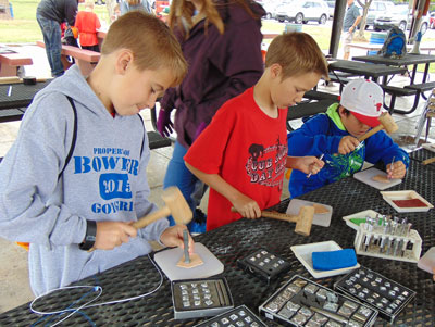 Local Cub Scouts work on stamping leather at an activity station at the Cub Scout Day Camp last weekend.  PHOTO BY STEPHANIE BUNKER/Moapa Valley Progress.