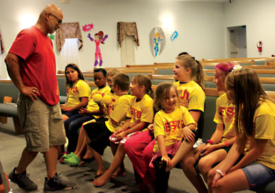 Calvary Community Church pastor Jason Ham helps a group of kids to learn rhythm and music during singing time at the church’s Vacation Bible School last week. PHOTO BY BRYNNE MCMURRAY/Moapa Valley Progress.