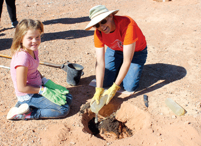 Dixie Wolf (right) of Logandale teaches and helps Gracielynn McKibbon, 8, of Overton to plant trees in the Public Lands day re-vegetation project at Logandale Trails. PHOTO BY MAGGIE MCMURRAY/Moapa Valley Progress.