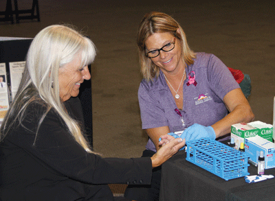 KathyJo Knight of Mesa View Hospital administers a blood type test for Marty Rapson of  Casablanca Resort during the Community Health Fair on Friday.  PHOTO BY VERNON ROBISON/Moapa Valley Progress.