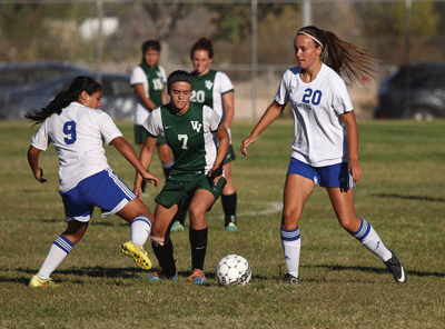 Xochitl Frias (left) and Ida Velthoven (right) double team Virgin Valley opponent Kallie Graves for possession of the ball in a home game last week. PHOTO BY DOROTHY ELY-SCOTT/Moapa Valley Progress.